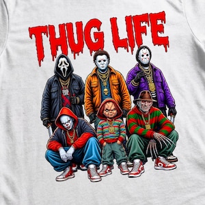 May include: A white t-shirt featuring a graphic print of six horror movie characters dressed in streetwear with gold chains. Above the characters, the text THUG LIFE is printed in a red, dripping font. The characters include figures in masks and costumes.