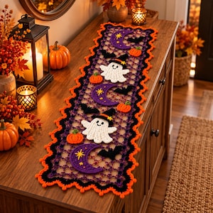 May include: A rectangular crochet table runner featuring a repeating pattern of white ghosts wearing black witch hats, purple crescent moons with yellow stars, small orange pumpkins, and black bats, all bordered by a scalloped orange edge.