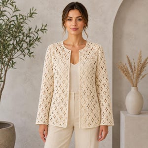 May include: A cream-colored, open-front jacket featuring an intricate, repeating geometric crochet pattern. The garment has long sleeves, a round neckline, and a straight hem, worn over a simple, solid-colored cream top and matching trousers.
