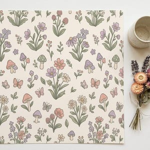 Peut inclure: Un set de table crème avec un motif répété de fleurs, de champignons et de papillons aux couleurs pastel. Une tasse beige et un petit bouquet de fleurs séchées sont à côté du set de table.