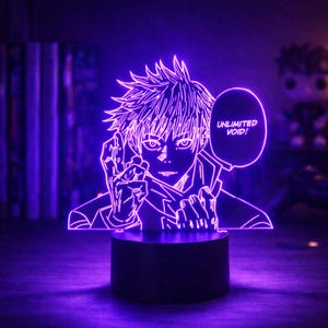 Puede incluir: Lámpara LED púrpura con una ilustración de estilo manga de un personaje con pelo puntiagudo. El personaje hace un gesto con la mano, con el texto "UNLIMITED VOID!" en un bocadillo. La lámpara está sobre una base negra.