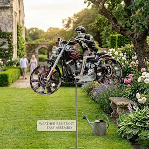 Könnte beinhalten: Metall-Gartenstecker mit einem Skelett-Fahrer auf einem Motorrad mit Flammendesign. Die Räder scheinen sich zu drehen. Das Schild lautet "WEATHER-RESISTANT EASY ASSEMBLY". Das Motorrad ist auf einer Metallstange in einem Garten montiert.