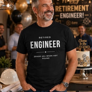 Könnte beinhalten: Ein schwarzes T-Shirt mit dem weißen Text "RETIRED ENGINEER" und dem Satz "ERROR 404 WORK NOT FOUND" darunter. Das Bild zeigt auch einen lächelnden Mann mit einer Uhr am Handgelenk und eine Party im Hintergrund.