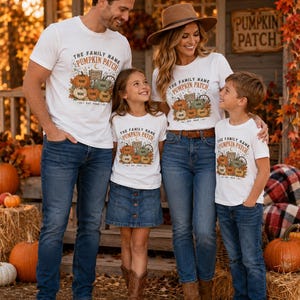 May include: A white short-sleeved t-shirt featuring a graphic of multiple pumpkins and the text THE FAMILY NAME PUMPKIN PATCH EST. YEAR. The design includes small labels reading NAME on each pumpkin. The shirt is worn with blue denim jeans.