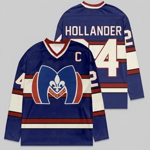 May include: Two blue hockey jerseys with white and red detailing. The front jersey features a large emblem with a fleur-de-lis design and the text "ESTD 1909". Both jerseys display the number "4" and the name "HOLLANDER".