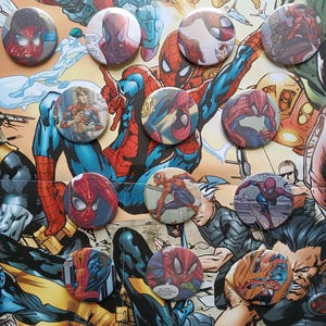 Könnte beinhalten: Eine Sammlung von zwölf runden Ansteckbuttons mit verschiedenen Comic-Illustrationen von Spider-Man in rot-blauen Kostümen. Jeder Button zeigt eine einzigartige Action-Pose oder ein Nahaufnahme-Porträt der Figur und präsentiert detaillierte Linienführung sowie lebendige Farben, die dem klassischen Superhelden-Grafikstil entsprechen.