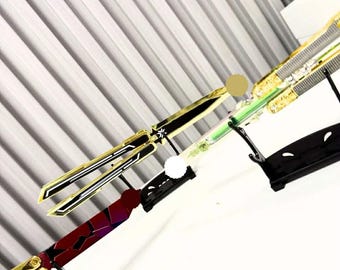 Könnte beinhalten: Drei Butterfly-Messer werden ausgestellt. Das obere Messer hat goldene und schwarze Akzente, das mittlere hat grün und gold, und das untere hat rot und gold. Der Text "Gaming needs Creations" ist sichtbar.