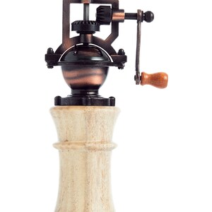 May include: A vintage-style manual pepper grinder with a wooden base and a metal grinding mechanism. The grinder has a crank handle and a copper-colored finish.