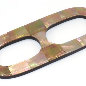 May include: A double-looped, iridescent, mother-of-pearl hair comb. The comb is made of a mosaic of small, iridescent squares.