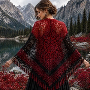 May include: A red and black crocheted shawl with fringe. The shawl is draped over the shoulders, with a detailed openwork pattern. The color gradient transitions from red to black, creating a striking visual effect. The shawl is a handmade accessory.