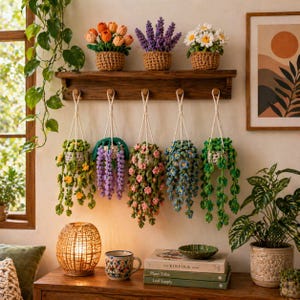 Puede incluir: Una exhibición de plantas de ganchillo hechas a mano, que incluye cestas colgantes y flores en macetas. La paleta de colores presenta tonos vibrantes de naranja, morado, amarillo, rosa, azul y verde. La escena está ambientada en una estantería y mesa de madera.