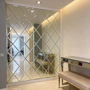 May include: A decorative wall mirror featuring a grid of diamond-shaped glass panels. The mirror reflects a room with neutral tones, including a hallway and furniture. The design creates a geometric pattern, enhancing the room's aesthetic.