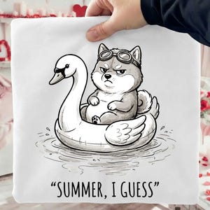 May include: A white square pillow with a cartoon illustration of a Shiba Inu dog wearing goggles, sitting on a swan float. The text "SUMMER, I GUESS" is printed at the bottom in black font. The dog has a grumpy expression.