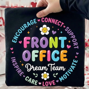 Può includere: Tessuto quadrato nero con le parole "FRONT OFFICE" in grandi lettere colorate. Il testo è circondato dalle parole "ENCOURAGE, CONNECT, SUPPORT, MOTIVATE, LOVE, CARE, INSPIRE" in un motivo circolare. Sono presenti anche le parole "Dream Team".