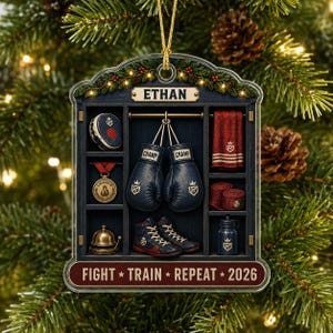 May include: A decorative ornament featuring a locker room scene with the name ETHAN at the top and the text FIGHT TRAIN REPEAT 2026 at the bottom. The locker contains dark blue boxing gloves, a gold medal, a red towel, shoes, and a water bottle.