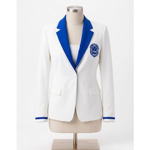 May include: A white blazer featuring a single-button closure, long sleeves with blue cuffs, and contrasting blue lapels. An embroidered blue crest with the text ZΦB is positioned on the left chest area, adding a distinct detail to the garment.