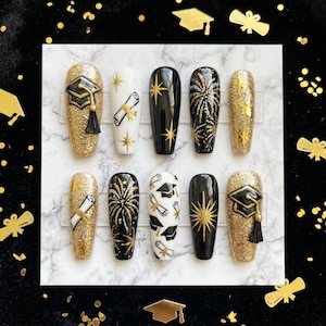 May include: A set of ten press-on nails with a graduation theme. The nails feature gold glitter, black, and white designs, including graduation caps, diplomas, and fireworks. Some nails have a gold glitter base, while others are black or white.