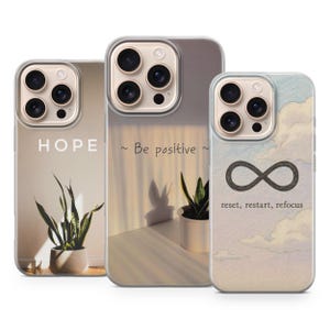 Pode incluir: Três capas de telefone transparentes com designs diferentes. Uma capa tem a palavra "HOPE" impressa, outra diz "Be positive", e a terceira apresenta um símbolo de infinito com as palavras "reset, restart, refocus". Cada capa tem um design de planta.