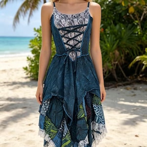 Könnte beinhalten: Blaues Kleid mit Spitzenoberteil und Spaghettiträgern. Das Kleid hat eine Corsagenfront und einen geschichteten Rock mit gemusterten Einsätzen und weißer Spitzentrimmung. Geeignet für Strand oder Freizeit.