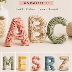 May include: A crochet alphabet pattern PDF featuring 6.5 cm letters. The image displays the letters A, B, and C in pink, beige, and green, respectively, along with the letters M, E, S, R, and Z in various colors. The text includes "Crochet Alphabet Pattern PDF".