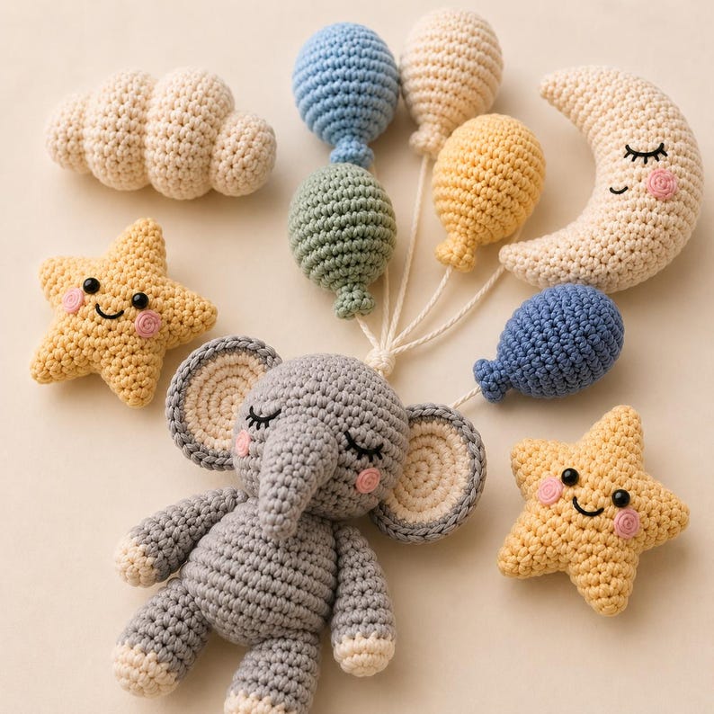 May include: A collection of crocheted items including a gray elephant, two yellow stars with smiling faces, a crescent moon with a sleeping face, a white cloud, and five small balloons in blue, cream, yellow, and green, all connected by white strings.