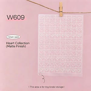 以下が含まれることがあります： 白いハートの輪郭のグリッドが特徴の、Heart Collectionのマット仕上げステッカーシート。シートは、ピンクの背景に対して、紐に木製のクリップで保持されています。テキストには「W609」、「1シート/パック」が含まれています。