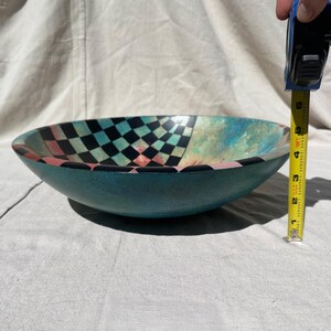K&ouml;nnte beinhalten: Eine t&uuml;rkisfarbene dekorative Sch&uuml;ssel mit einem Schachbrettmuster in Schwarz, T&uuml;rkis und Rosa. Die Sch&uuml;ssel hat einen Durchmesser von ca. 15 cm und ein einzigartiges, k&uuml;nstlerisches Design. Die Sch&uuml;ssel besteht aus einem gl&auml;nzenden Material.