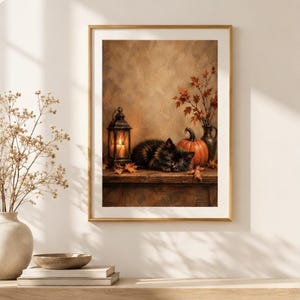 Könnte beinhalten: Ein gerahmter Kunstdruck, der eine dunkelhaarige Katze zeigt, die auf einer Holzoberfläche neben einer leuchtenden Laterne, einem orangefarbenen Kürbis und einer Vase mit herbstlich gefärbten Blättern vor einem strukturierten braunen Hintergrund schläft.