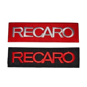 Op de afbeelding: Twee rechthoekige patches met het woord "RECARO" geborduurd. Eén is rood met zilveren letters, de andere zwart met rode letters. Deze patches zijn waarschijnlijk voor auto- of racekleding.