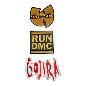 Könnte beinhalten: Drei gestickte Aufnäher mit Musiklogos. Der obere Aufnäher ist ein gold-schwarzes Wu-Tang Clan Emblem. Der mittlere Aufnäher ist ein quadratisches, schwarz-goldenes Run DMC Logo. Der untere Aufnäher ist ein weiß-rotes Gojira Logo mit gezackter Schrift.