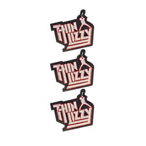 Puede incluir: Tres parches bordados idénticos con el texto Thin Lizzy en letras blancas de bloque con bordes rojos sobre un fondo negro. Cada parche incluye una silueta blanca de una persona tocando la guitarra sobre el texto.