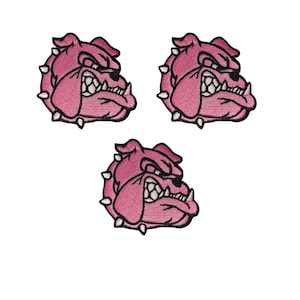Puede incluir: Tres parches bordados rosas con la imagen de un bulldog. Cada parche presenta una cabeza de bulldog detallada con una expresión de enfado, dientes visibles y un collar con púas. Los parches están sobre un fondo blanco.