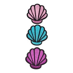 May include: Three embroidered patches shaped like seashells, arranged vertically. The top shell is light pink, the middle shell is bright turquoise, and the bottom shell is deep purple. Each patch features a glittery texture and black borders.