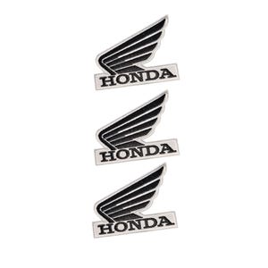 Peut inclure: Trois écussons brodés identiques présentant le logo Honda, composé d'une forme d'aile noire stylisée placée au-dessus du mot HONDA en lettres capitales noires, le tout sur un fond blanc avec une fine bordure blanche.