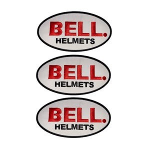 Puede incluir: Tres parches bordados con el texto "BELL HELMETS" en rojo sobre un fondo ovalado blanco, con un borde negro. Los parches son probablemente para cascos de motocicleta o equipo relacionado.