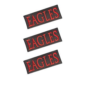 以下が含まれることがあります： 赤い太字の大文字で「EAGLES」と刺繍された、3枚の長方形の黒いワッペン。各ワッペンは縁が綺麗に処理されており、白い背景に対して垂直な列に並べられています。