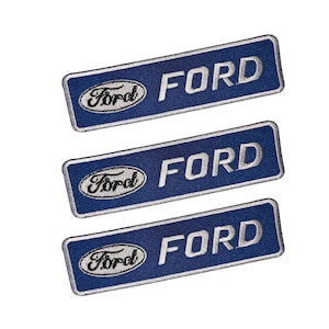 Könnte beinhalten: Drei blau-weiße, gestickte Aufnäher mit dem Wort "FORD" in weißen Großbuchstaben. Das Ford-Logo ist in Weiß und Schwarz auf jedem Aufnäher gestickt. Die Aufnäher sind rechteckig mit abgerundeten Ecken.