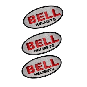 Pode incluir: Três patches bordados ovais cinzentos com o texto vermelho "BELL HELMETS". Os patches têm uma borda preta e são exibidos em um fundo branco.