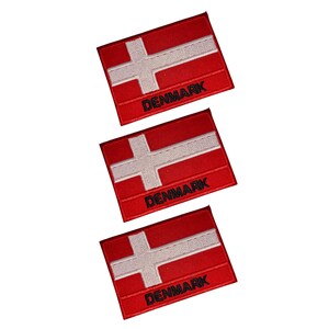 Könnte beinhalten: Drei rot-weiß gestickte Aufnäher mit der Flagge Dänemarks. Jeder Aufnäher hat ein weißes skandinavisches Kreuz auf rotem Grund, mit dem Wort "DENMARK" in Schwarz gestickt.