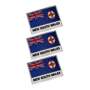 May include: Three embroidered patches featuring the New South Wales flag. Each patch has a blue background with the Union Jack in the upper left corner and a white circle with a red cross and crown in the upper right. The text "NEW SOUTH WALES" is embroidered in white.