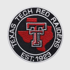 Puede incluir: Un parche bordado circular con fondo negro, una silueta roja del estado de Texas y un logotipo de doble T en blanco y rojo en el centro. El texto del borde dice Texas Tech Red Raiders y Est. 1923 en hilo blanco sobre un campo negro.