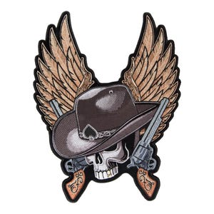 Puede incluir: Un parche bordado que muestra una calavera con un sombrero de vaquero marrón oscuro con un emblema de pica negro en la banda. Dos revólveres cruzados con empuñaduras de color marrón claro se sitúan tras la calavera, enmarcados por grandes alas.