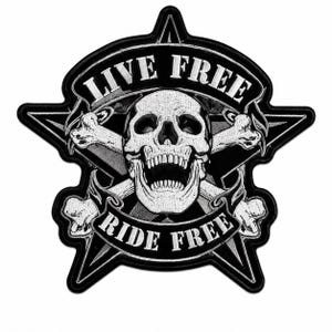 May include: A black and white embroidered patch shaped like a five-pointed star. The design features a central human skull with crossed bones behind it. Banners above and below the skull display the text LIVE FREE and RIDE FREE in white.