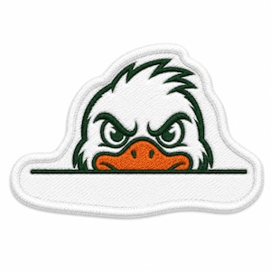 Puede incluir: Parche bordado con un pato blanco con pico naranja y detalles verdes. El pato tiene una expresión intensa, con un contorno verde y un espacio en blanco para texto. El parche está bordeado con costuras blancas.