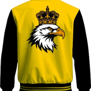 May include: A yellow varsity jacket with black sleeves and black ribbed trim featuring yellow stripes. The back displays a large graphic of a white and black eagle head wearing a detailed black and yellow crown, centred on the yellow back panel.