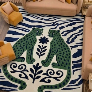 May include: A large area rug featuring a bold design with two green spotted leopards facing each other. The rug has a cream-colored background with a navy blue and white zebra stripe pattern and decorative floral elements.