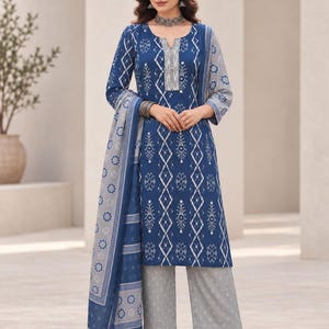 May include: A blue knee-length tunic with a white geometric pattern and a notched neckline, paired with light grey wide-leg trousers featuring a small white print. A matching blue and grey patterned shawl drapes over the shoulder.