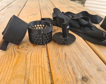 May include: A black hand wrap roller tool featuring a cylindrical frame with a hexagonal honeycomb pattern, a central winding spindle, and a long black fabric hand wrap. The device is designed for winding boxing or martial arts wraps.