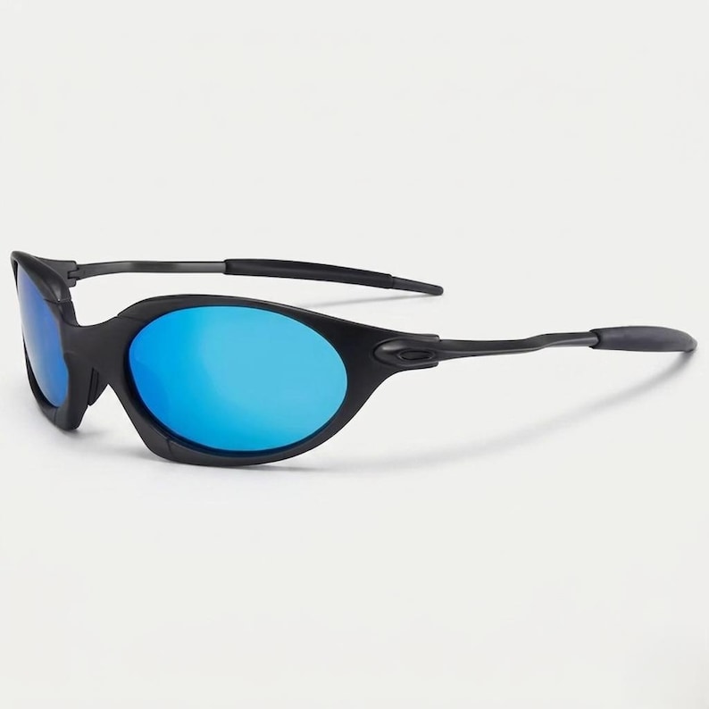Puede incluir: Gafas de sol negras con lentes azules. Las gafas tienen un dise&ntilde;o elegante y curvado con un acabado mate. Las lentes son de un azul vibrante, contrastando con las monturas negras. Las patillas de las gafas son finas y se extienden hasta las orejeras.