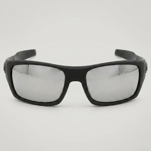 May include: Black sunglasses with rectangular frames and mirrored lenses. The sunglasses have a thick, matte black frame and a sporty design. The lenses reflect light, creating a silver appearance.